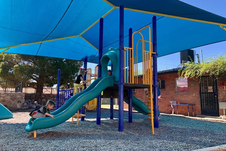 Young children playing on a blue playground slide