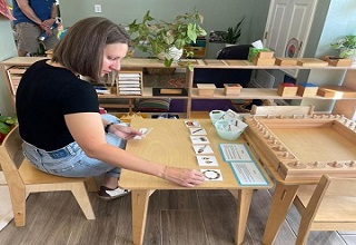 Female parent in a black t-shirt learning how to use Montessori materials during an onsite workshop at Mountain West Montessori in El Paso
